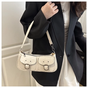 Close-up of off-white vintage shoulder bag featuring dual front pockets with bronze buckles