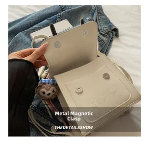 Detail of white PU leather bag featuring magnetic buckle closure and 3D bear embossing