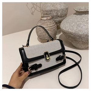 Detailed close-up of a black and white woven square handbag with gold hardware