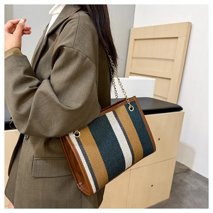 Detail of vintage woven tote bag with vertical brown and green stripes and gold chain