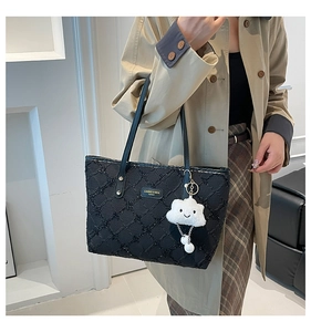 Detail of black sequined tote bag with metal logo and white cloud plush charm