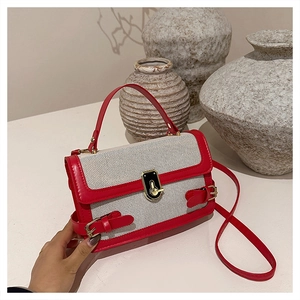 Close-up of red and white crossbody bag with gold metal clasp and woven texture