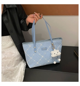 Detail of light blue quilted tote bag with floral embroidery and cloud pendant