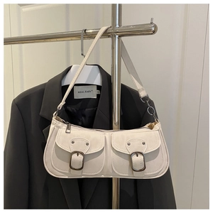 Detail view of cream vintage baguette bag featuring dual front pockets and metal buckles