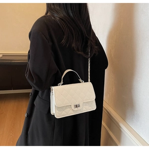 Rear view of a model wearing a white quilted crossbody bag with a metal chain strap
