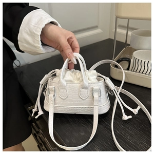 Close-up of white croc-embossed mini handbag featuring a drawstring inner pouch