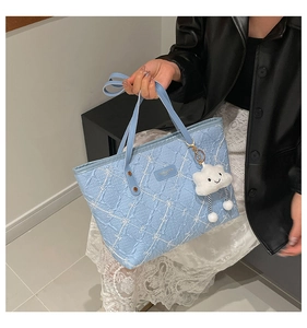Detail of light blue quilted tote bag with bow stitching and plush cloud charm