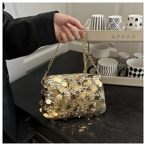Detalle de un bolso de noche con lentejuelas doradas, cadena de metal y superficie brillante
