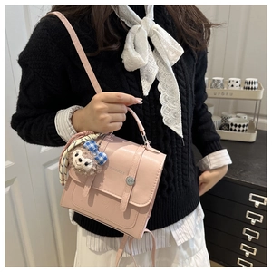 Detail of pink vintage PU leather handbag with embossed letters and cute plush charm