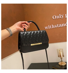 Detalle del bolso de cuero acolchado negro con costuras onduladas y hebilla dorada