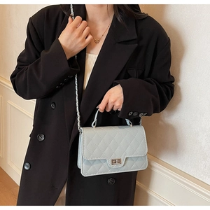 Close-up of quilted light blue shoulder bag with silver turn-lock and metal chain strap
