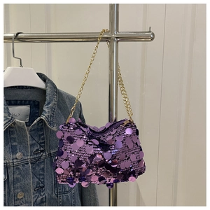 Detail der lila Pailletten-Handtasche mit goldener Kette neben einer Jeansjacke