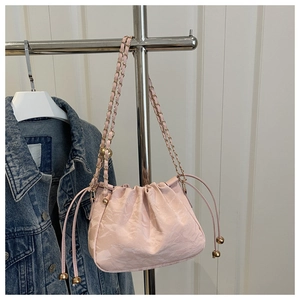 Dettaglio della borsa a secchiello rosa con coulisse e tracolla in catena dorata