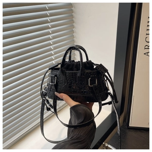 Gros plan d'un mini sac à main noir en cuir motif crocodile avec cordon de serrage