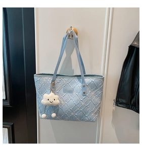 Detail of light blue quilted tote bag with floral patterns and cloud plush charm