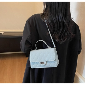 Detail of light blue quilted leather handbag with silver twist lock and chain strap