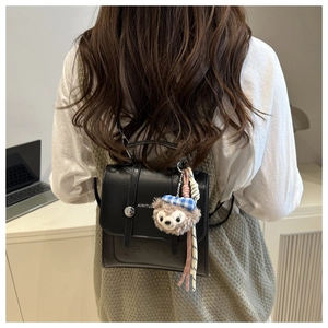 Detail of black PU leather backpack with silver turn-lock and Duffy bear charm