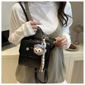 Detail view of black vintage leather dual-use bag with a cute plush bear charm