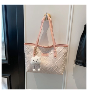 Detail of pink textured tote bag with diamond pattern and cute cloud plush charm