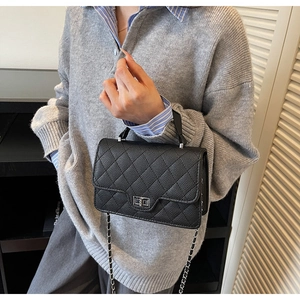Detail of black quilted leather crossbody bag with silver twist lock and chain strap