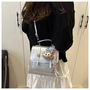 Silver metallic mini bag with character relief and plush charm worn as a backpack