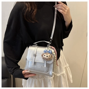 Detail of silver metallic handbag with embossed character and ShellieMay plush charm