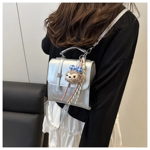 Detail of silver metallic textured bag with embossed lid and cute plush bear charm