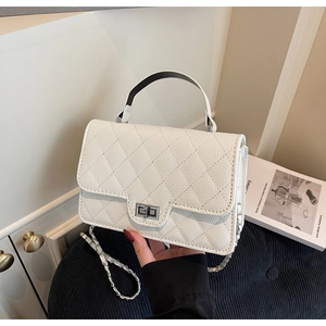 Detail of white quilted crossbody bag with silver twist lock and leather chain strap