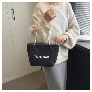 Detail of minimalist black canvas tote bag with woven handles and side pocket