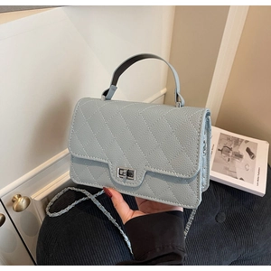 Detail of light blue quilted leather handbag with silver twist lock and chain strap
