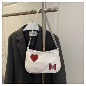 Close-up of white PU leather underarm bag featuring red heart and letter M patches