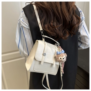 Macro shot of a cream leather backpack featuring a 3D bear motif and plush charm detail