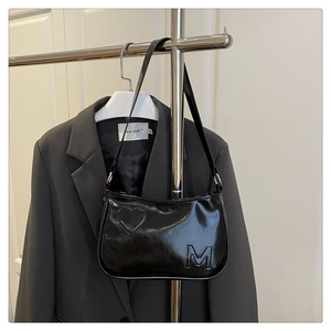 Detail of black glossy leather armpit bag with heart pattern and silver metal hardware