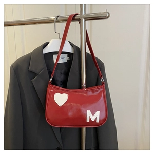 Detail view of red leather shoulder bag with white heart and letter M patchwork design