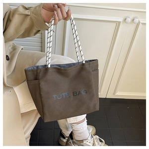 Macro detail of the brown canvas tote bag with woven rope handles and TOTE BAG print