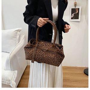 Detail of leopard print tote bag featuring brown leather handles and metal hardware ring