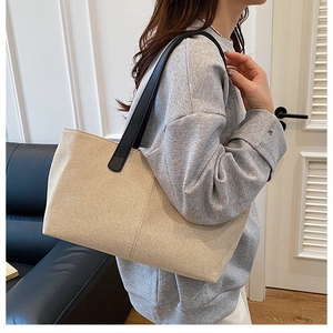 Close-up of large canvas tote bag with black leather shoulder straps on a person