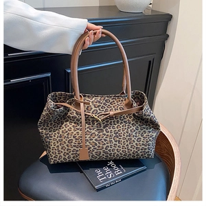 Detail of leopard print tote bag with brown leather handles and drawstring accents