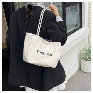 Side view of a vintage canvas tote bag with woven straps worn by a model in casual style