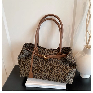 Detail of leopard print tote bag with brown leather handles on a decorative book