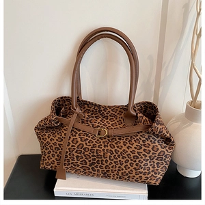 Detail of leopard print tote bag with brown leather straps and gold metal D-ring buckle