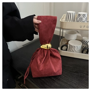 Close-up of vintage burgundy drawstring bag with a polished golden oval metal ring detail