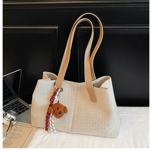Detail of beige woven tote bag with brown PU straps and a cute plush dog pendant