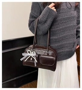Détail du sac à bandoulière marron foncé avec pendentif nœud en dentelle et cœur