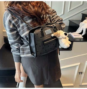 Chic dark grey polka dot backpack with a cute white plush puppy charm in a street setting