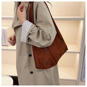 Detail of laser-cut floral patterns on dark brown suede shoulder tote bag for women
