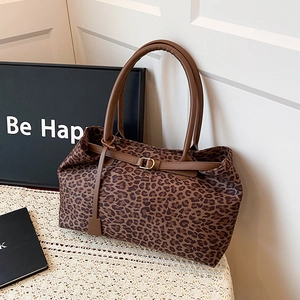 Leopard print tote bag with brown leather handles and gold buckle on a lace surface