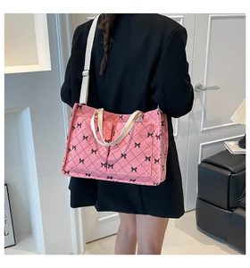 Pink corduroy tote bag with black bow print and quilted details shown on shoulder