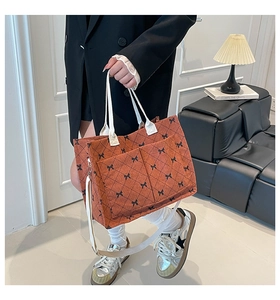 Detail of orange corduroy tote bag with black bow pattern and adjustable white strap