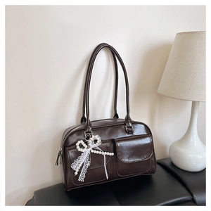 Détail du sac sous le bras marron foncé brillant avec poches avant et breloque en dentelle